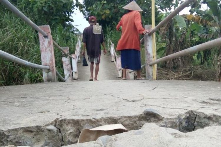 Dua warga Desa Kebonbatur,  Kecamatan Mranggen,  Kabupaten Demak,  Jateng,  melintad di jembatan Dongko yang retak dan miring akibat diterjang banjir bandang,  Minggu ( 29/1/2017 )