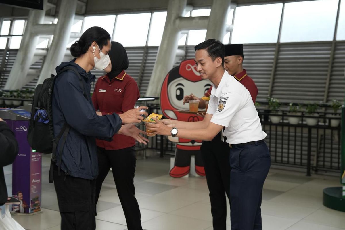 Petugas LRT Jabodebek membagikan takjil kepada pengguna di salah satu stasiun.
