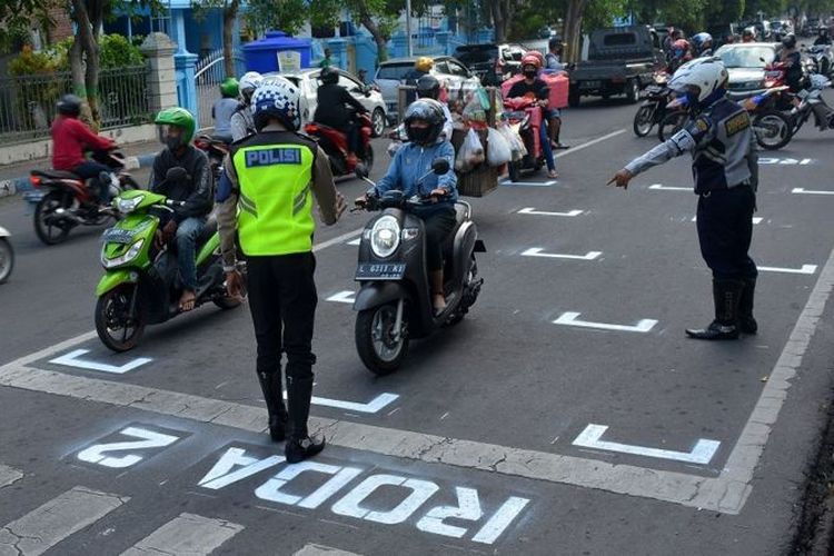 Petugas Dinas Perhubungan dan polisi mengarahkan pengendara motor berhenti di belakang garis untuk menjaga jarak antarpengendara di Jalan Wahid Hasyim, Kabupaten Jombang, Rabu (15/07)