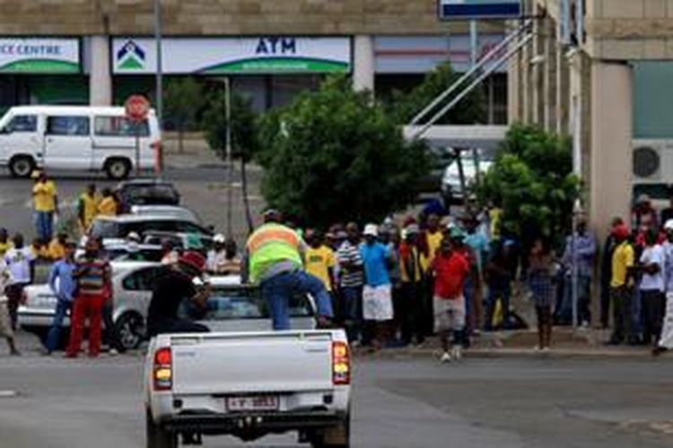 Sejumlah anggota polisi naik ke sebuah van yang membawa jenazah seorang pria yang tewas dalam baku tembak di dekat Istana Kerajaan di Maseru, Lesotho, pada Minggu (1/2/2015). 