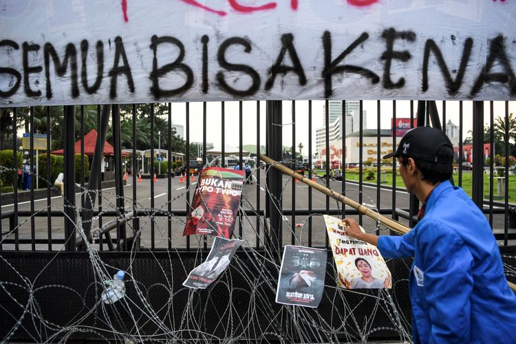 Mahasiswa menempelkan poster saat aksi unjuk rasa di depan Gedung DPR, Senayan, Jakarta, Selasa (28/6/2022). Pengunjuk rasa yang berasal dari berbagai universitas tersebut menolak pengesahan Rancangan Kitab Undang-Undang Hukum Pidana (RKUHP). ANTARA FOTO/M Risyal Hidayat/aww.
