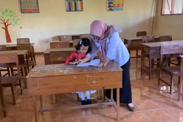 Meski sendirian masuk kelas 1 SDN 1 Setono, Kecamatan Jenengan, Kabupaten Ponorogo, Jawa Timur tak membuat Ira (7) ciut nyali. Mengenakan baju terusan warna atas merah bawah biru muda, diantar kakeknya, Ira percaya diri masuk ke dalam kelas,Senin (17/7/2023) pagi.   
