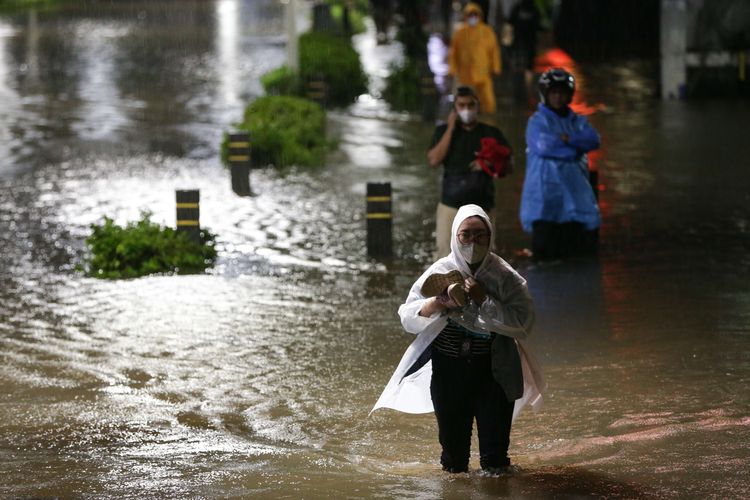 Warga melintasi banjir yang mengenang kawasan Kemang, Jakarta Selatan, Kamis (6/10/2022) malam. Hujan deras yang mengguyur wilayah Jakarta siang menyebabkan Jalan Kemang Raya, Jakarta Selatan, terendam banjir.