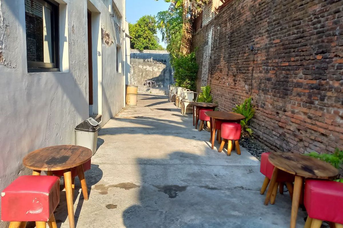 Kaledupa Solo, kafe hidden gem di dalam gang. Meja dan kursi kafe ditata di sepanjang gang dan sebuah bangunan bekas gudang.