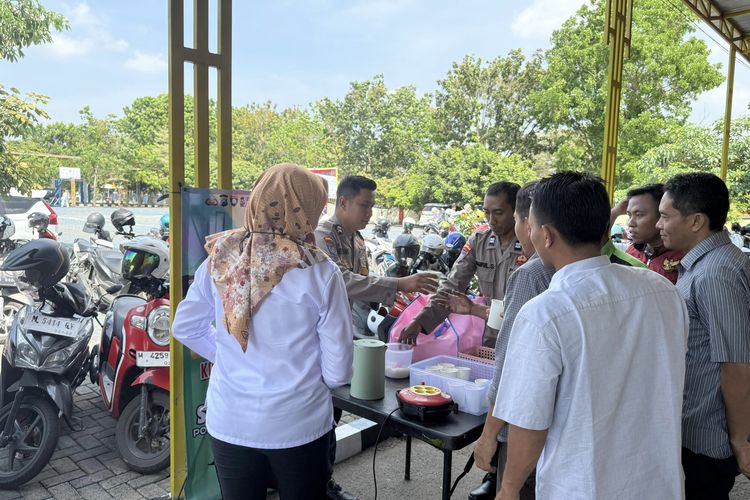Bhabinkamtibmas Desa Sembilangan, Briptu Herlambang Wahyu Anafis Satriatama saat melayani pembagian kopi gratis di depan kantor layanan SKCK Polres Bangkalan, Rabu (17/9/2025). 