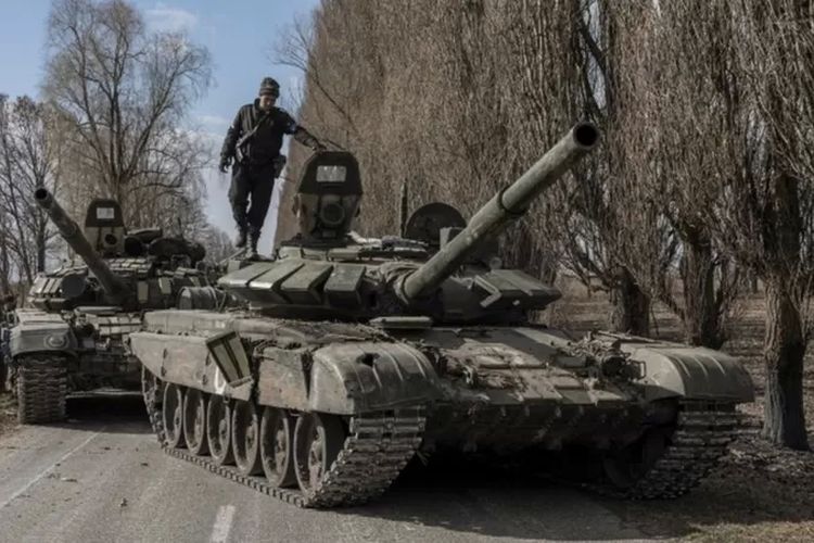 Seorang prajurit Ukraina berdiri di atas tank Rusia yang ditangkap setelah pertempuran di desa Lukyanivka di luar Kyiv, 27 Maret 2022.