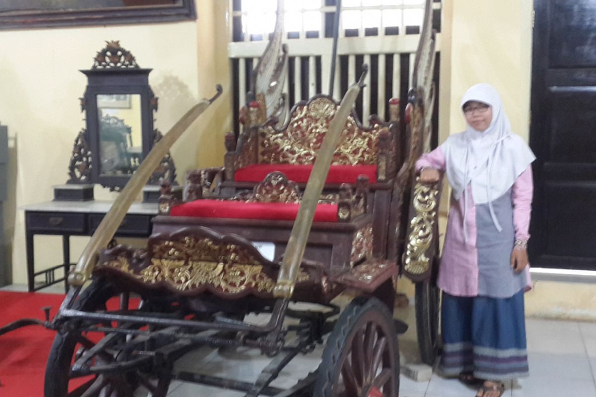 Seorang wisatawan saat berfoto bersama kereta kebesaran Arya Wiraradja yang usianya sudah hampir 1.000 tahun di Museum Keraton Sumenep, Minggu (2/7/2017).