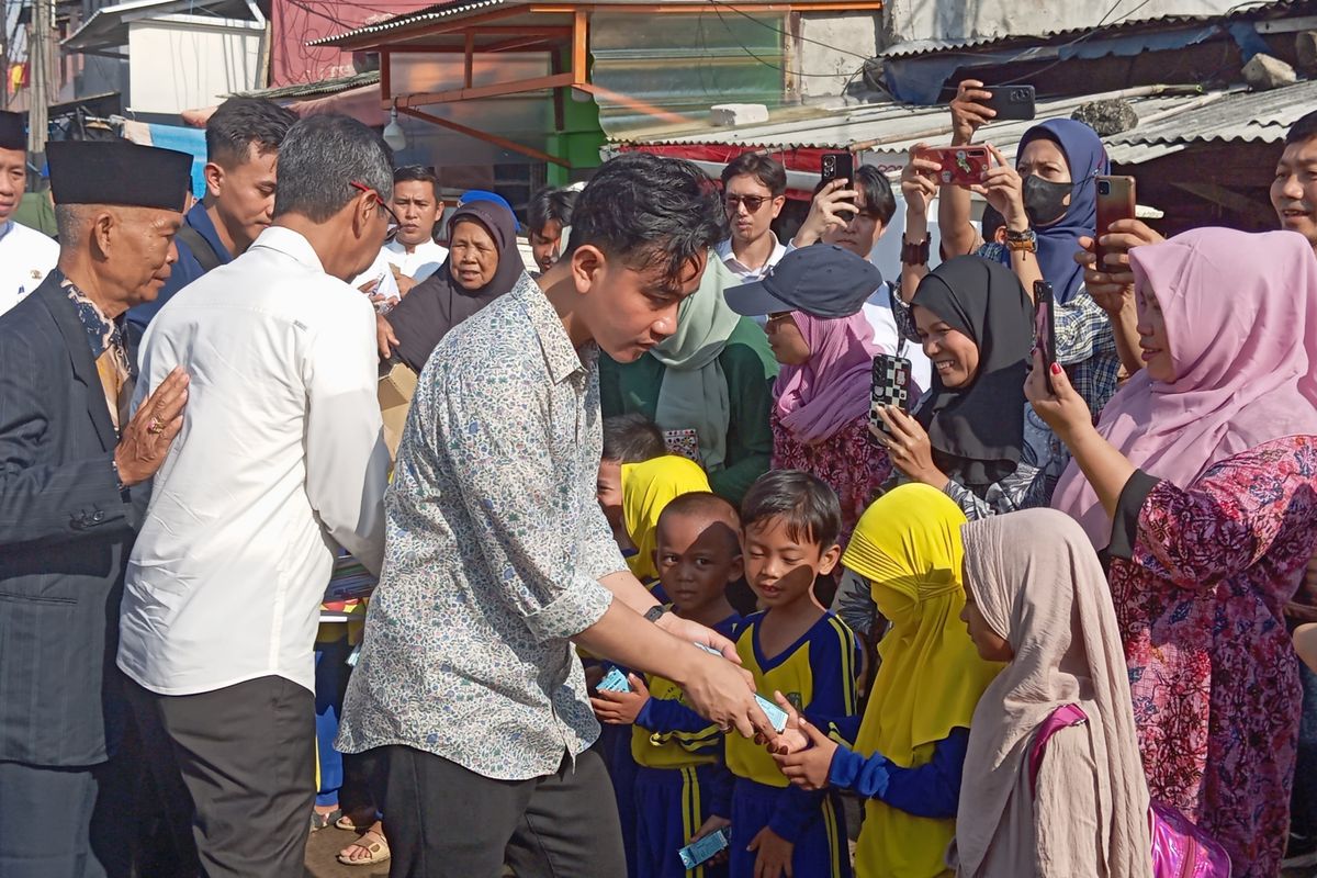 Wakil Presiden Terpilih Gibran Rakabuming Raka dan Pj Gubernur DKI Jakarta Heru Budi Hartono saat membagikan susu di Kamal Muara, Jakarta Utara, Jumat (28/6/2024)