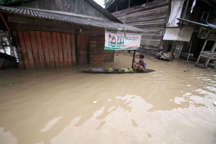 Seorang anak mengangkut tabung gas dengan perahu di tengah banjir yang merendam Desa Buket Linteueng, Kecamatan Langkahan, Aceh Utara, Aceh, Senin (23/1/2023). Menurut Badan Penanggulangan Bencana Daerah (BPBD) Aceh Utara, hujan deras yang mengguyur Aceh Utara dalam dua hari terakhir mengakibatkan tujuh kecamatan di Aceh Utara terendam banjir dan sebanyak 11.202 jiwa warga terdampak banjir serta 420 jiwa mengungsi.