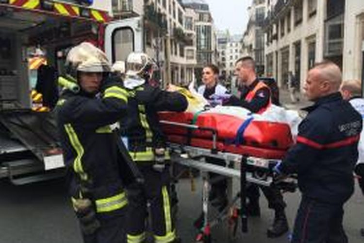 Tim medis membawa seorang korban luka serangan maut ke kantor majalah satir Charlie Hebdo di Paris, Perancis, Rabu (7/1/2014), yang menewaskan 12 orang termasuk pemimpin redaksi majalah tersebut.