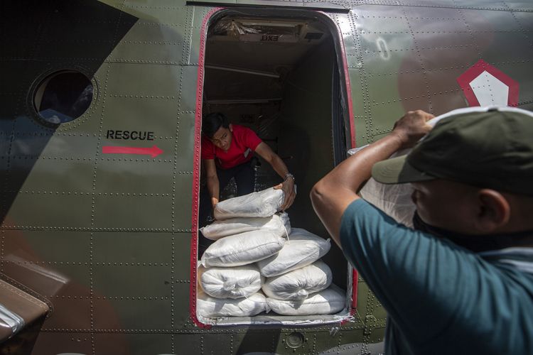Prajurit TNI AU dibantu petugas memindahkan karung yang berisi garam ke dalam pesawat Cassa C-212 saat persiapan operasi TMC.