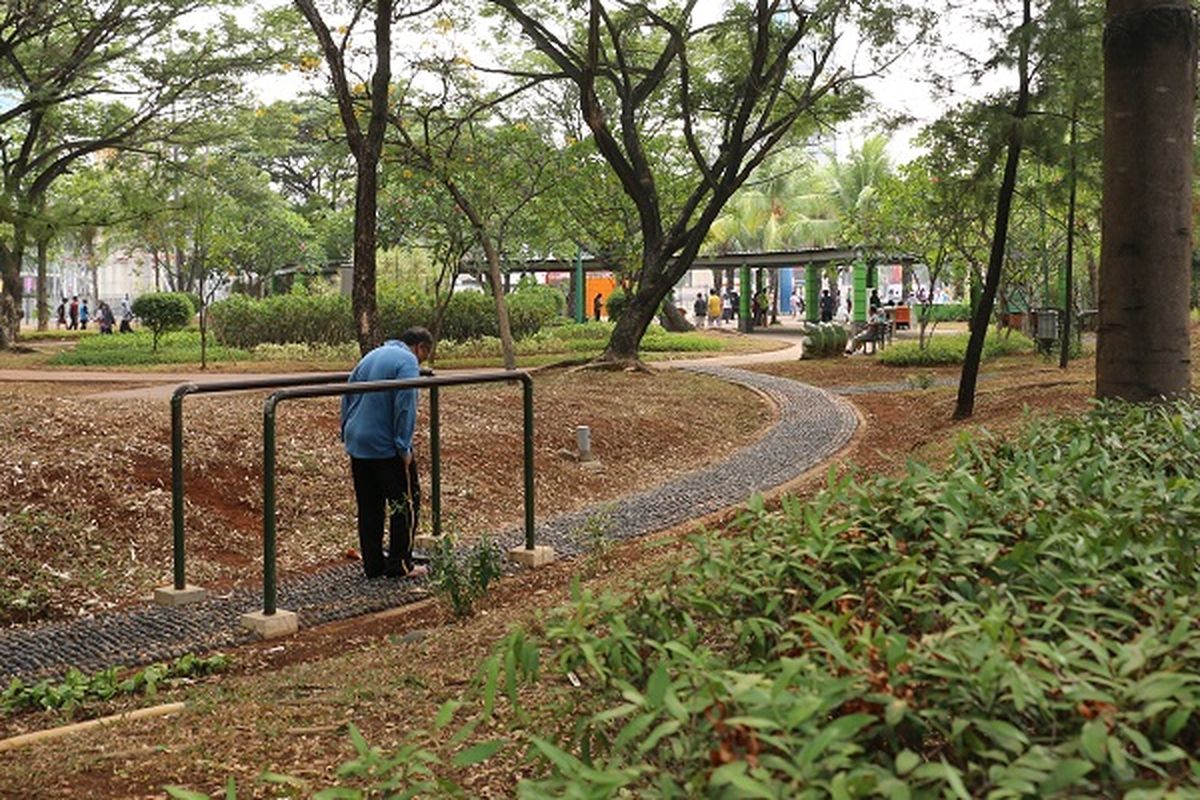 Terlihat ssatu orang tua sedang menikmati fasiltias trek reflreksi yang ada di salah satu Taman Kota di DKI Jakarta