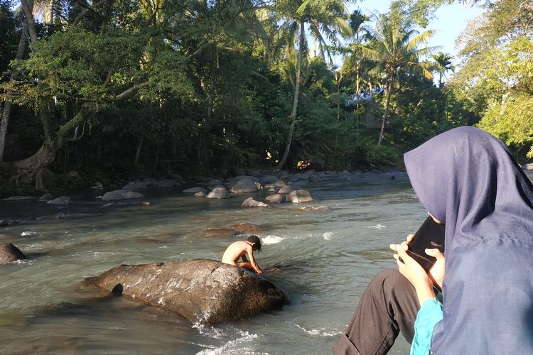 Wisatawan menghabiskan waktu di Sungai Meninting, Desa Batu Mekar, Lombok Barat, Nusa Tenggara Barat. Sungai berbatu ini memiliki air yang jernih. 
