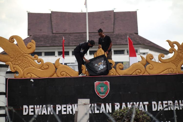 Dua orang massa aksi demonstrasi Aliansi Reformasi KUHAP saat mengibarkan bendera One Piece di depan Kantor DPRD Kalteng, Palangka Raya, Jumat (1/8/2025).