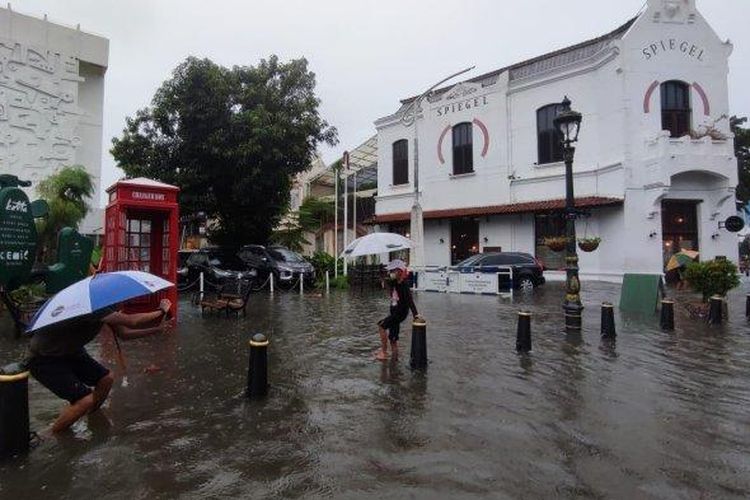 Wisatawan asal Bogor Ali bersama anaknya Nafis tetap menikmati suasana Kota Lama Semarang meski dalam kondisi banjir