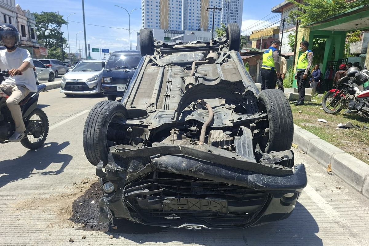 Pengendara mobil terbalik saat melaju di Jalan Gatot Subroto, Kota Medan pada Minggu (20/7/2025) siang. Akibatnya,  seorang driver ojek online terluka. 