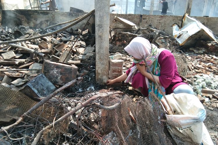 Mila (26) salah seorang pedagang di Pasar Jatisari, Karawang, tengah memungut puing-puing sisa kebakaran, Jumat (25/10/2019).