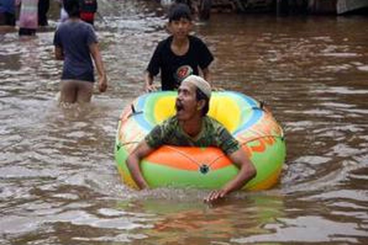 Warga memanfaatkan perahu karet sebagai alat trasportasi saat banjir melanda di Jalan Perintis Kemerdekaan, Jakarta Timur, Senin (19/1).