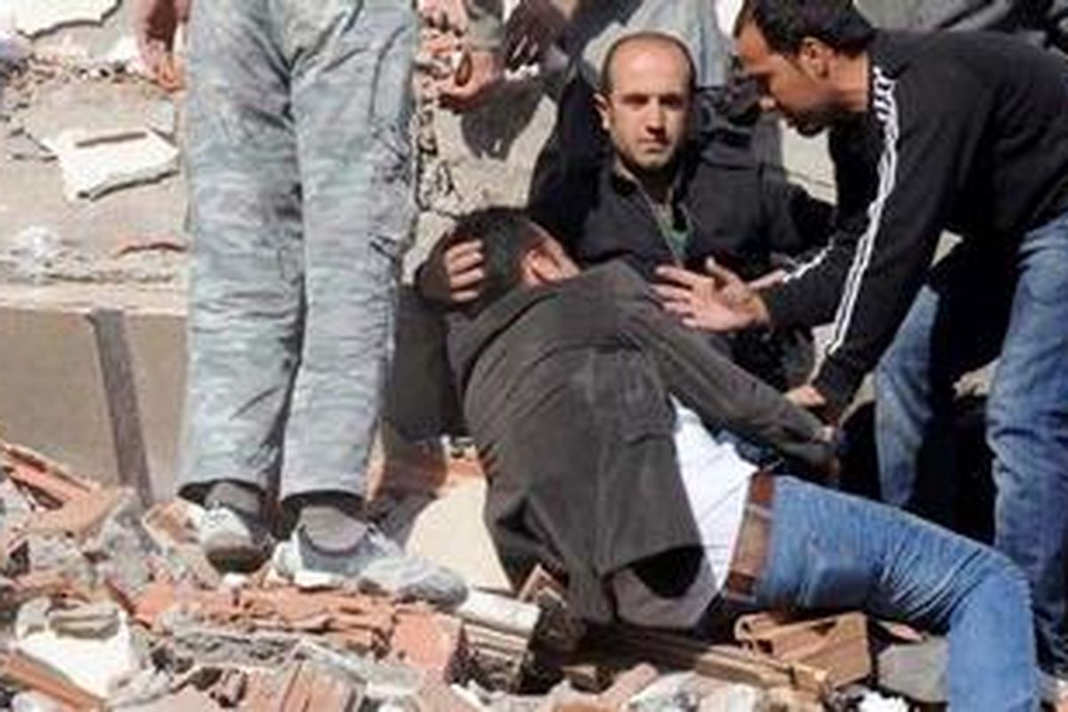 Warga berada di bangunan yang hancur diguncang gempa 7,3 magnitud di Desa Tabanli, di timur Provinsi Van, Turki, Minggu (23/10/2011).