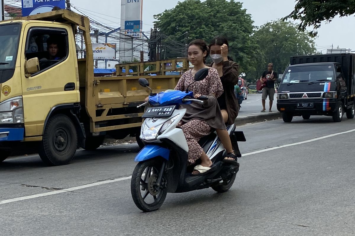 Pengendara motor berboncengan tanpa menggunakan helm di jalan raya