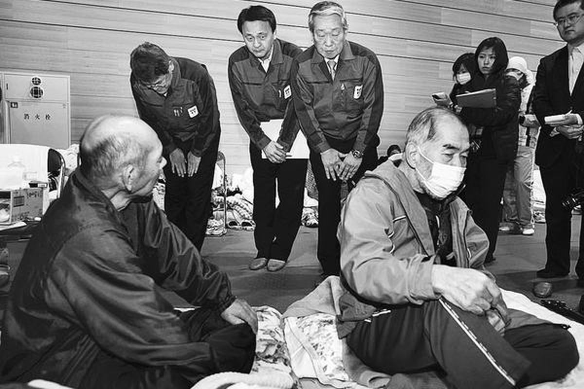 Wakil Presiden Tokyo Electric Power Co (Tepco) Norio Tsuzumi (berdiri ketiga dari kiri) menunduk dan meminta maaf kepada para warga lansia, yang terpaksa dievakuasi dari sekitar lokasi pembangkit listrik tenaga nuklir milik Tepco di Prefektur Fukushima. Direksi Tepco menemui para warga lansia itu di penampungan sementara di kota Tamura, Fukushima, Selasa (22/3).