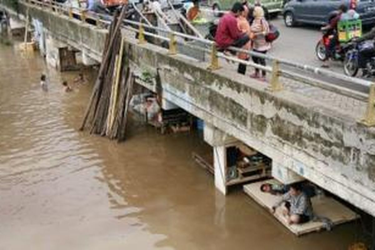 Warga tetap bertahan di tempat tinggal mereka yang dikepung air luapan Sungai Ciliwung di bawah jalan layang Jalan KH Abdullah Syafei, Kampung Melayu, Jakarta, Senin (22/7/2013).