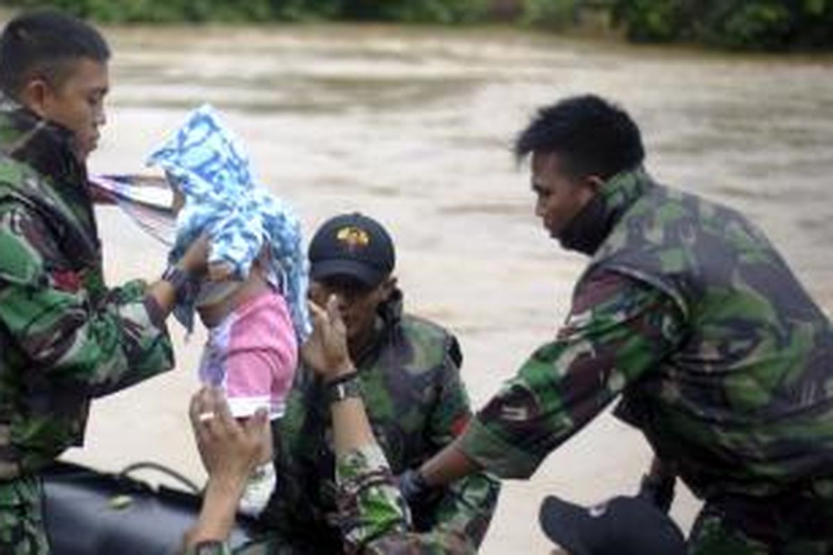 Personel TNI mengevakuasi bayi dari luapan Kali Ciliwung di Jalan Jatinegara Barat Raya, Jakarta Timur, Sabtu (18/1/2014).