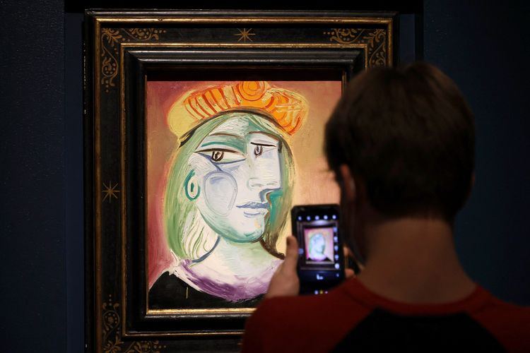 Seorang pengunjung mengambil foto lukisan Femme au beret rouge-oranye di pameran lukisan dan keramik Pablo Picasso di Bellagio Gallery of Fine Art di Bellagio Resort & Casino pada 21 Oktober 2021 , di Las Vegas, Nevada. Pameran ini menampilkan 11 karya yang akan ditawarkan pada lelang langsung, Picasso: Masterworks from the MGM Resorts Fine Art Collection, oleh Sotheby's & MGM Resorts pada 23 Oktober di Bellagio. 