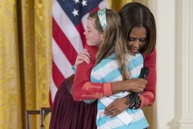 MIchelle Obama memeluk Charlotte Bell (10) setelah bocah itu menyerahkan salinan curriculum vitae milik ayahnya yang tiga tahun belakangan sulit mencari pekerjaan.