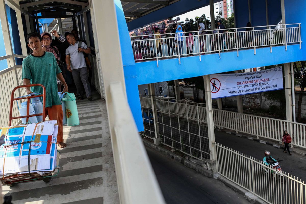 Spanduk larangan melintas bagi pejalan kaki di Jalan Jatibaru Raya terpasang di bawah Jembatan Penyeberangan Multiguna (skybridge) saat pejalan kaki melintas di Jalan Jatibaru Raya, Jakarta, Sabtu (9/2/2019). Pemprov DKI Jakarta mewajibkan pejalan kaki menggunakan skybridge saat melewati Jalan Jatibaru Raya yang menuju atau keluar dari Stasiun Tanah Abang, Pasar Blok F, Blok G dan Jalan KS Tubun agar lebih tertib dan terbebas dari pedagang kaki lima (PKL).