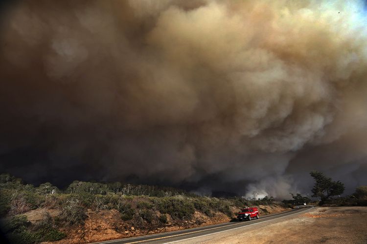 Kepulan asap membubung tinggi di Highway 1 utara Santa Cruz County, akibat sambaran petir yang memicu kebakaran hutan besar di California, Amerika Serikat, Rabu (19/8/2020).