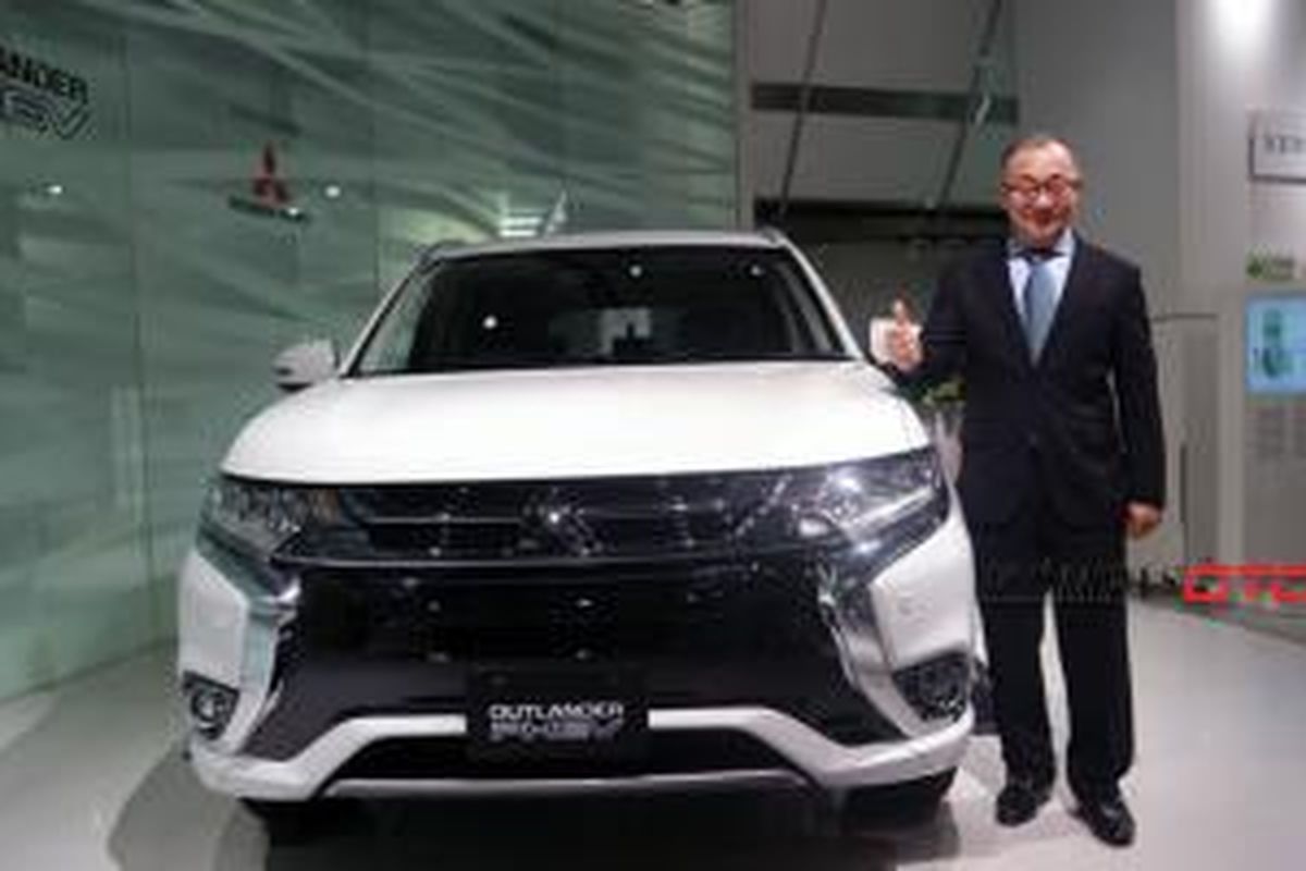 Corporate General Manager of Desain Office Mitsubishi Motors Corporation (MMC) Tsunehiro Kunimoto berpose bersama Outlander PHEV di kantor pusat MMC di Tokyo, Jepang, Selasa (27/10/2015).