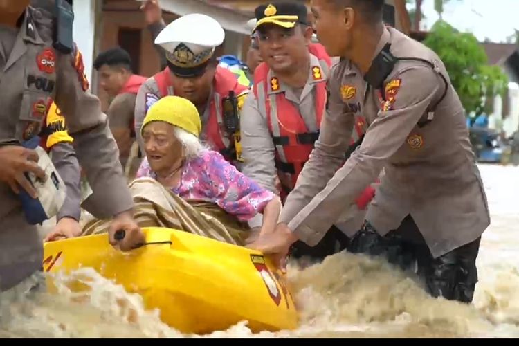 Petugas kepolisian Polres Rohul saat mengevakuasi salah seorang wanita lansia yang terjebak banjir di dalam rumahnya, di Desa Babussalam, Kecamatan Rambah, Kabupaten Rokan Hulu, Riau, Selasa (26/12/2023).
