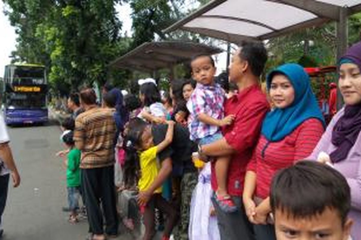 Keluarga Elva Kurnia Dewi (kanan) tengah menunggu bus tingkat di selter Balaikota, Jakarta, Rabu (31/7/2014). Libur Lebaran ini dijadikan ajang memperkenalkan anak kepada angkutan umum.