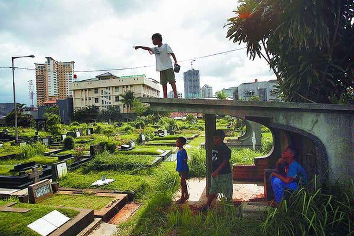 Alpin (atas) bermain layang-layang di Tempat Pemakaman Umum Petamburan, Kecamatan Tanah Abang, Jakarta Pusat, Senin (17/3). Minimnya ruang terbuka hijau dan terdesaknya tempat tinggal warga miskin di Jakarta membuat kuburan menjadi tempat bermain dan berkumpul anak-anak.  