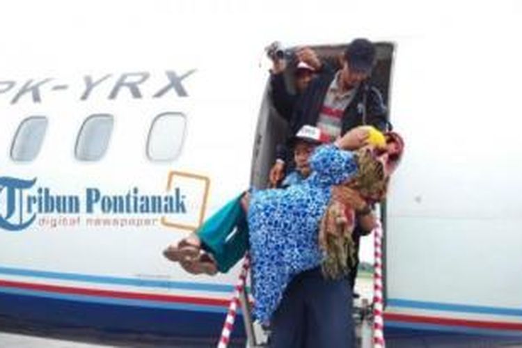 Seorang penumpang perempuan pesawat Trigana Air dibopong keluar pesawat karena syok. Penerbangan Trigana Air tujuan Pangkalan Bun, transit via Ketapang akhirnya kembali ke Bandara Supadio Pontianak, Kubu Raya, Kalimantan Barat, Rabu (31/12/2014) pukul 09.42 WIB. 