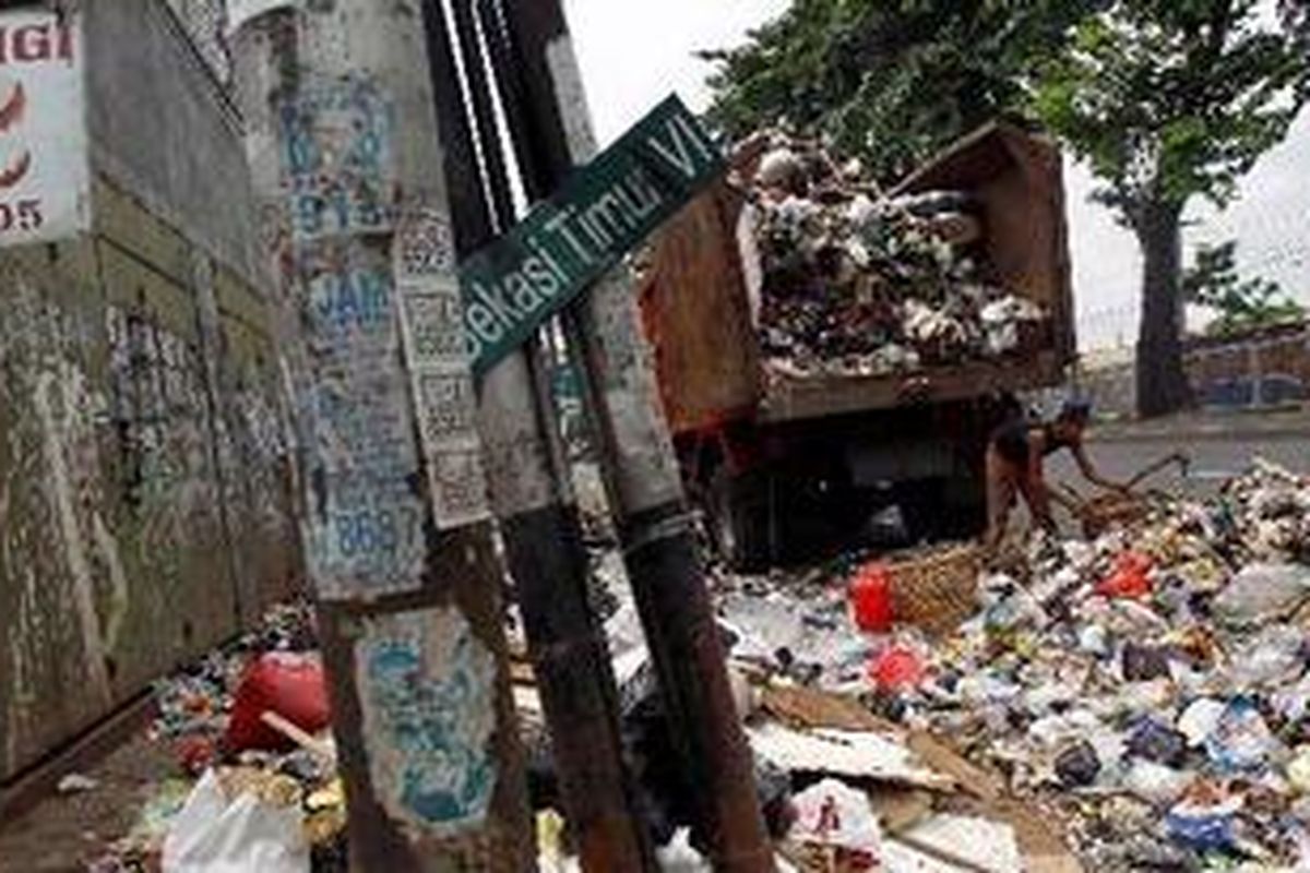 Pekerja mengumpulkan sampah untuk diangkut ke atas truk sampah di Jalan Bekasi Timur Raya, Jakarta Timur, Kamis (20/1/2011). Penduduk DKI Jakarta yang berjumlah sekitar 9,5 juta orang ditambah sekitar dua juta warga komuter menghasilkan volume sampah sekitar 6.500 ton per hari.  