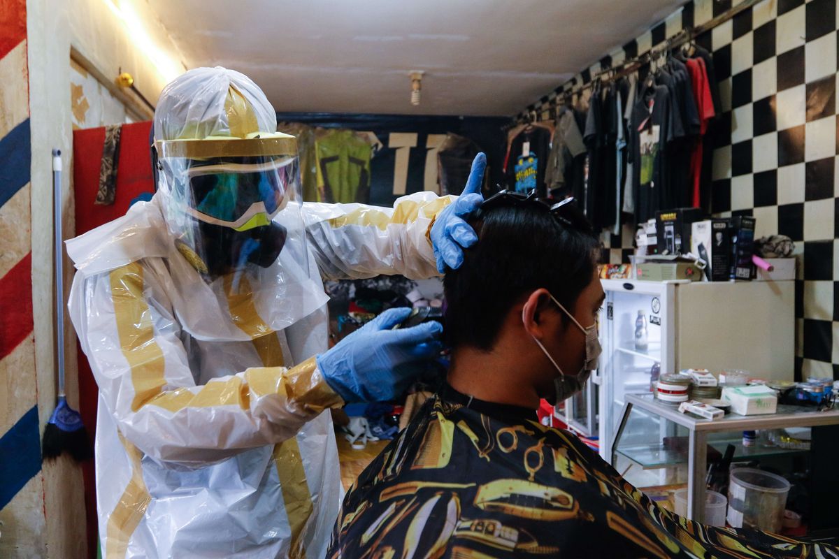 Herman Maulana Syah (40) tengah mencukur rambut pelanggan di Chemot Barbershop miliknya di Kampung Babakan, Desa Banjarwaru, Kecamatan Ciawi, Bogor, Jawa Barat, Senin (6/4/2020). Herman mengaku menggunakan alat pelindung diri (APD) saat bekerja untuk mengurangi resiko penularan wabah virus Covid-19.