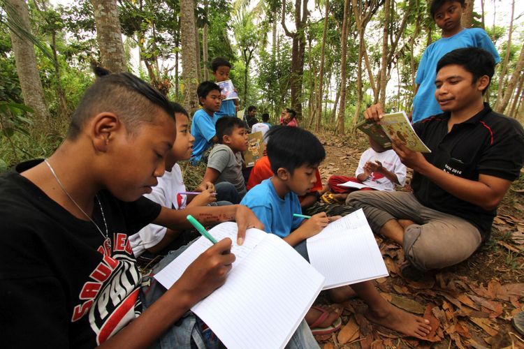 Relawan mendampingi anak-anak menulis proses mencapai cita-citanya di sekolah alam Kampung Batara di Papring, Banyuwangi, Jawa Timur, Minggu (24/9). Kegiatan edukasi tersebut bertujuan untuk memperkuat literasi pada anak-anak sekolah alam yang terletak di pinggir hutan produksi perhutani. ANTARA FOTO/Budi Candra Setya/foc/17.