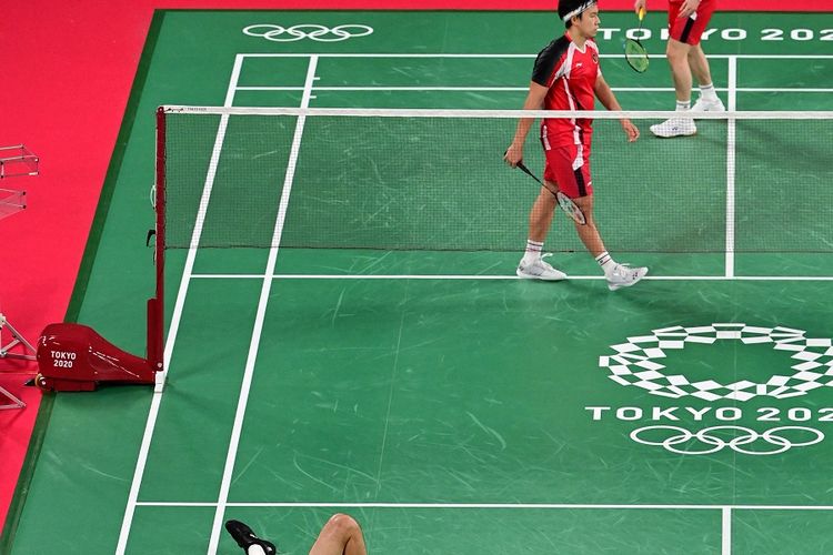 Ganda putra Indonesia Marcus Fernaldi Gideon dan Kevin Sanjaya Sukamuljo (atas) dalam penyisihan grup ganda putra melawan Wang Chi-lin-Lee Yang dari Taiwan pada Olimpiade Tokyo 2020 di Musashino Forest Sports Plaza di Tokyo pada 27 Juli 2021.