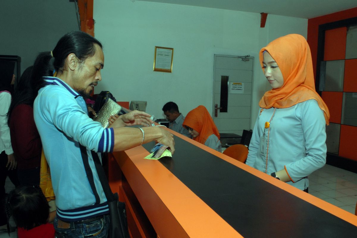 Seorang warga sedang mengambil uang kiriman yang diserahkan petugas di loket pelayanan Kantor Pos Cabang Sukabumi, Jawa Barat, Senin (5/6/2017). 