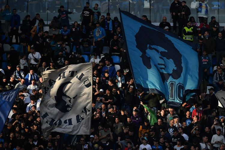 Suporter Napoli mengibarkan bendera dan memberikan dukungan dalam laga Liga Italia 2022-2023 antara Napoli vs Udinese di Stadion Diego Armando Maradona, 12 November 2022. Laga pekan ke-32 antara Napoli vs Salernitana, Minggu (30/4/2023) berpotensi menasbihkan Napoli sebagai juara Liga Italia 2022-2023.  (Photo by Tiziana FABI / AFP)