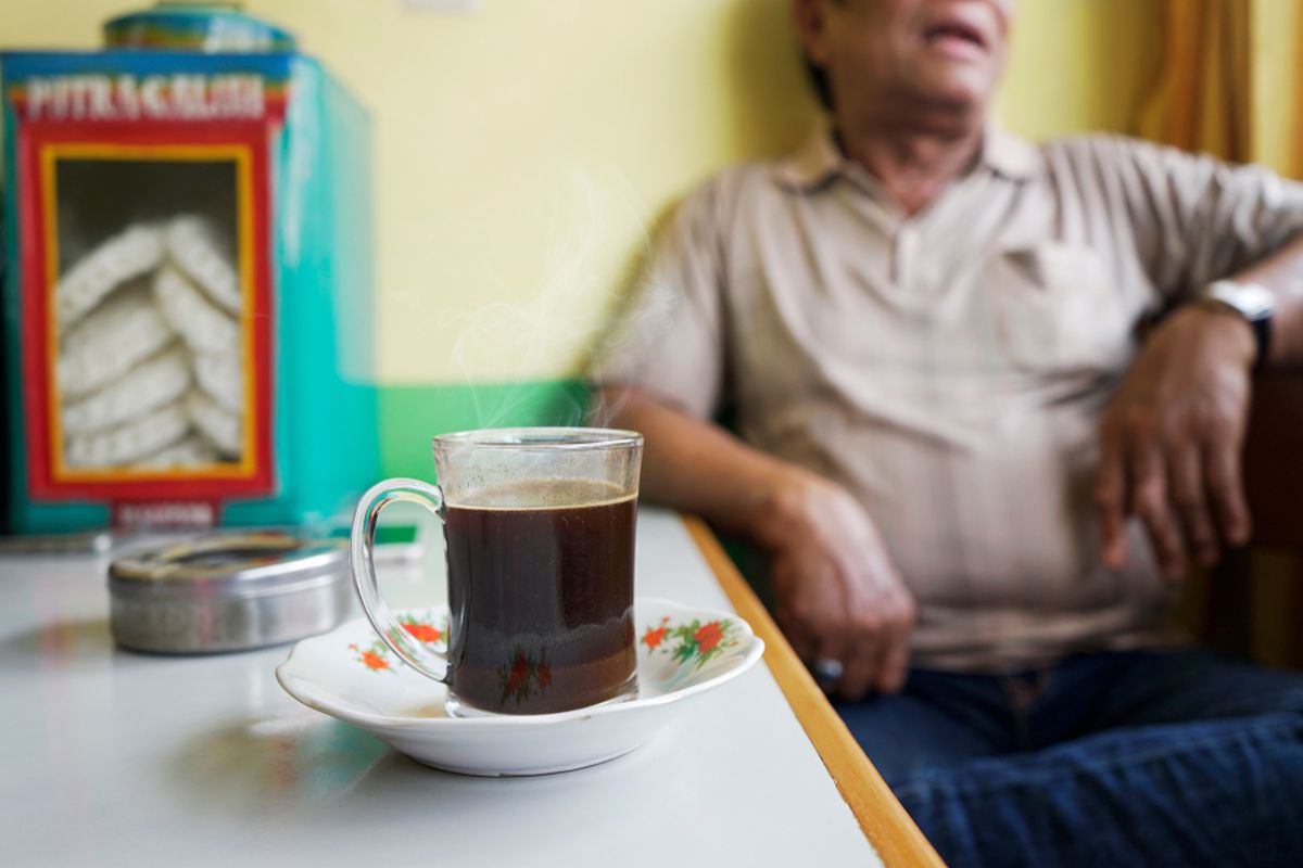 Ilustrasi orang Indonesia minum kopi tubruk. 