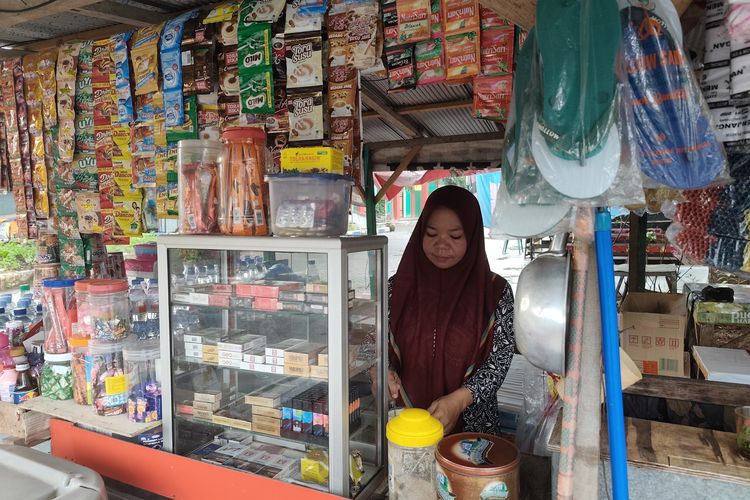 Aminah saat melayani pembeli di warung.