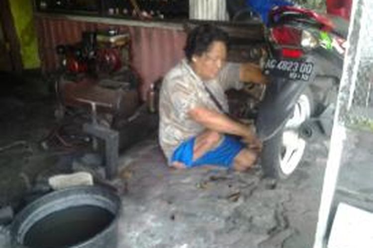 Kasiani saat proses melakukan penambalan ban dibengkel sederhananya di Jalan Jaksa Agung Suprapto Kota Kediri, Jawa Timur. 