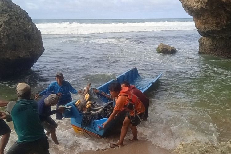 Warga dan petugas Satlinmas mengevakuasi kapal yang terbalik di Pantai Nglolang, Tanjungsari, Gunungkidul, Kamis (30/10/2025)