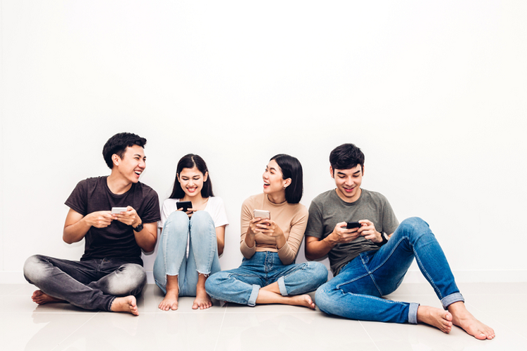 Sekelompok anak muda bersantai sambil mengakses aplikasi media sosial