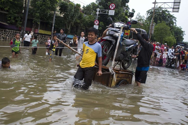 Sejumlah warga mengevakuasi sepeda motor yang terendam banjir di Jl. Raya Pondok Gede, Kramat Jati, Jakarta Timur, Rabu (1/1/2020). Luapan air Kali Baru sebabkan wilayah Kramat Jati terendam hingga sebahu orang dewasa.