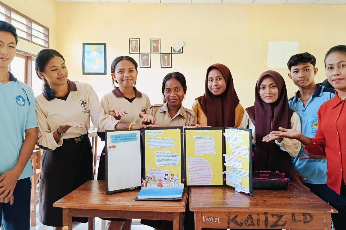 Elisabet Sabu Sogen (33) guru Sejarah di Sekolah Menengah Atas (SMA) Negeri 1 Adonara Barat, Kabupaten Flores Timur, Nusa Tenggara Timur (NTT), bersama siswa-siswinya dalam kegiatan pembelajaran materi dengan menggunakan media grafis bekas.