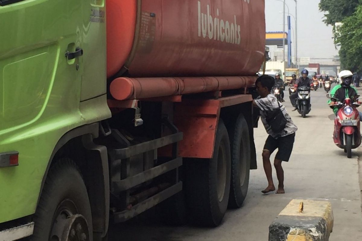 Manto (24 tahun) memgambil muatan oli dari sebuah truk tangki di Jalan Yos Sudarso, Jakarta Utara, Selasa (3/7/2018).